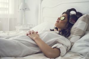 Women relaxing in bed with cucumber slices on her eyes.